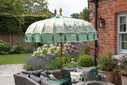 Riviera Mint handmade Balinese-style parasol with grey outdoor seating, botanical cushions and English garden planting
