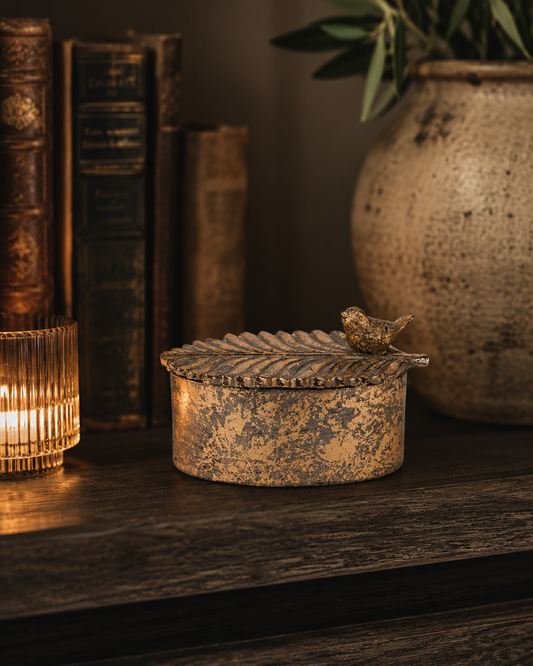 Antique gold bird trinket box with decorative leaf lid shown from the front.